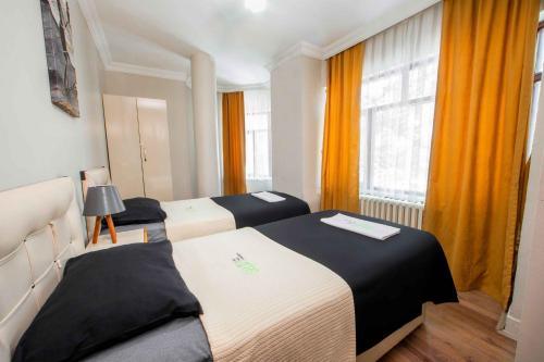 2 camas en una habitación con cortinas naranjas en Seyir Evleri DİVAN, en Kayseri