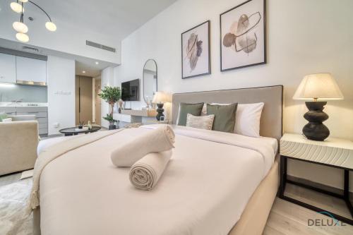 a bedroom with a large white bed and a living room at Classic Studio at Mesk 1 Midtown Dubai Production City by Deluxe Holiday Homes in Dubai