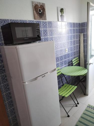 a white refrigerator with a microwave on top of it at Casa da laranjeira in Montargil