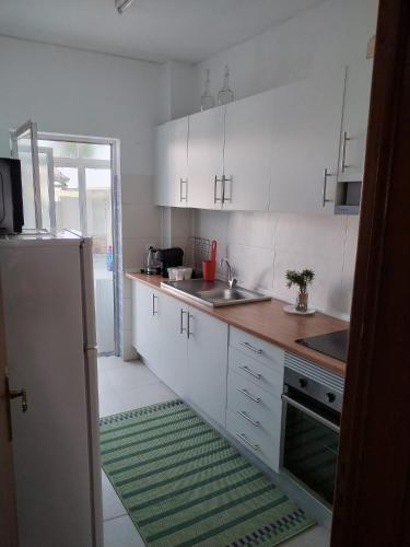 a kitchen with white cabinets and a green rug at Casa da laranjeira in Montargil