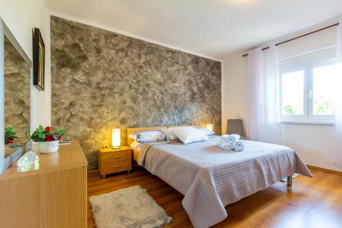 a bedroom with a bed and a stone wall at Chubi 2BR apt parking terrace bbq vegetable garden in Zadar