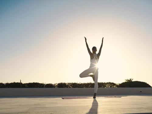 a woman dancing in the sun with her arms in the air at Canaves Epitome - Small Luxury Hotels of the World in Oia