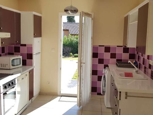 - une cuisine avec un évier et du carrelage pourpre sur le mur dans l'établissement Appartement T3 climatisé avec jardin et terrasse à 200m de la plage de Cavalaire - FR-1-100-249, à Cavalaire-sur-Mer