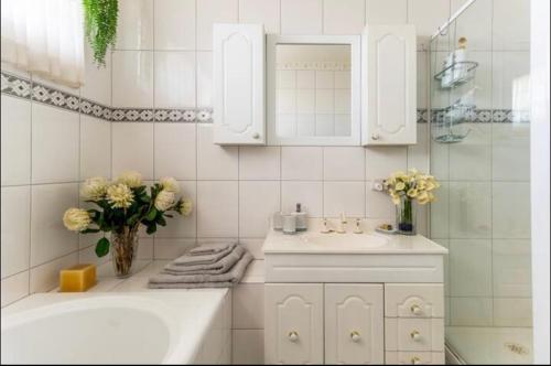 a white bathroom with a sink and a tub at Cosy private room easy access to city & airport in Melbourne