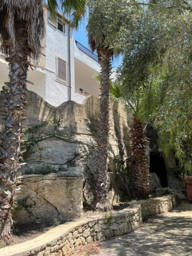 a building with palm trees and a stone wall at VILLA FRANCA in Fontane Bianche