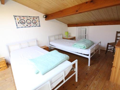 deux lits dans une chambre avec parquet dans l'établissement Maison de vacances 3 pièces à Saint-Pierre-d'Oléron, 4 couchages, terrasse, animaux acceptés - FR-1-246A-110, à Saint-Pierre-dʼOléron