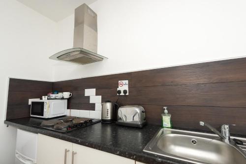 a kitchen counter with a sink and a microwave at Snooze Apartments in Bradford