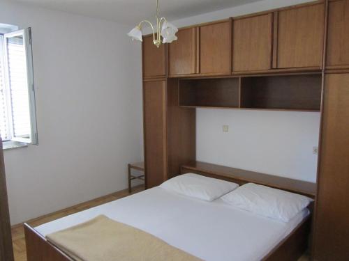 a bedroom with a bed and wooden cabinets at Apartments Antonia in Malinska