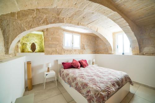 a bedroom with a bed in a stone wall at Vallettastay Standard Apartments in Valletta in Valletta