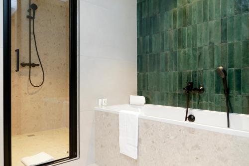 uma casa de banho com um chuveiro, uma banheira e um lavatório. em Le Richebourg Hôtel, Restaurant & Spa em Vosne-Romanée