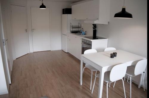uma cozinha branca com uma mesa branca e cadeiras brancas em Storklinta Skidcenter - Lägenhet em Jörn