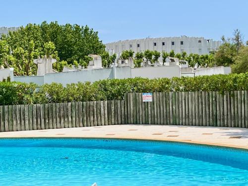 a swimming pool in front of a wooden fence at LE BALI, Exceptionnel P3 avec piscine à 2 min des plages , parking, wifi et climatisation in La Grande-Motte