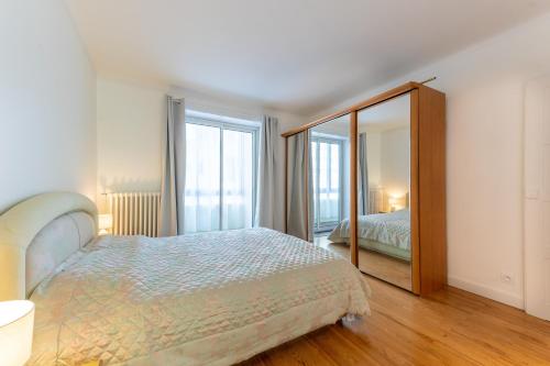 une chambre avec un lit et un grand miroir dans l'établissement L'Amédée - Appt à 500m du lac, à Annecy