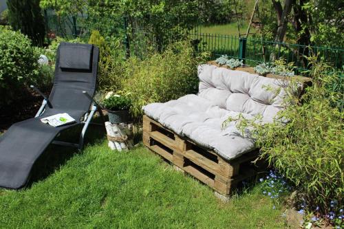 a bench in the grass next to a chair at Fränkische Seenliebe in Gunzenhausen