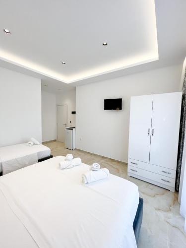 two beds in a room with white walls at Ionian View B&B in Himare