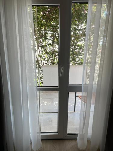 a window with white curtains in a room at Apartments Mrdak in Bar