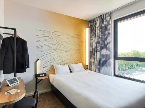 アルジャントゥイユにあるB&B HOTEL Argenteuilのベッド、デスク、窓が備わるホテルルームです。