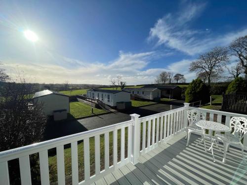 a deck with a white railing and a table and a chair at Stonewood Premium - 2 bedroom VS04 in Tenby