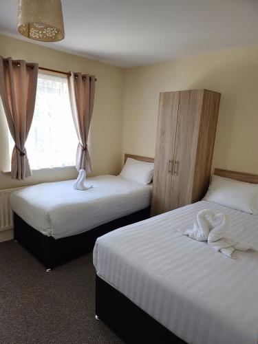two beds in a hotel room with a window at Lovely Private Room in Dublin
