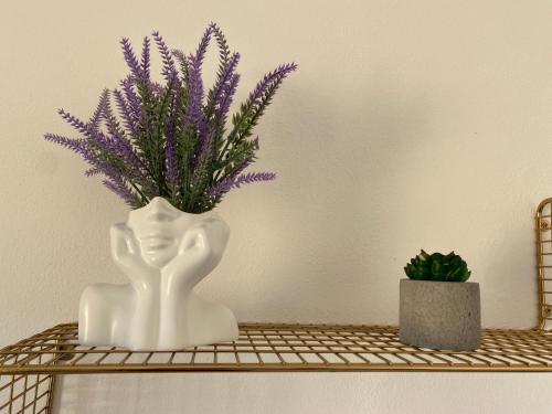 a white vase with purple flowers on a shelf at Casa Luana - Rooms in Sagres