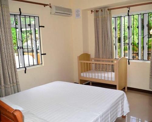a bedroom with a bed and a crib and windows at Jet Villa in Flic-en-Flac