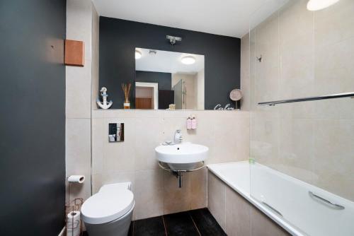 a bathroom with a sink and a toilet and a tub at Cozy 2BR London Flat with Workspace and City Views in London