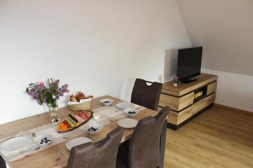 a dining room table with a plate of food and a television at Fränkische Seenliebe in Gunzenhausen