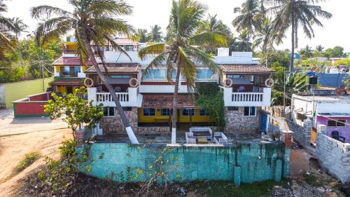 a house on a hill with palm trees in front of it at Mermaid Island Beach Resorts in Puducherry