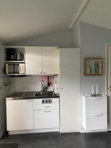 Il comprend une cuisine équipée d'appareils électroménagers blancs et d'un réfrigérateur blanc. dans l'établissement Liten ”stuga”, à Falkenberg