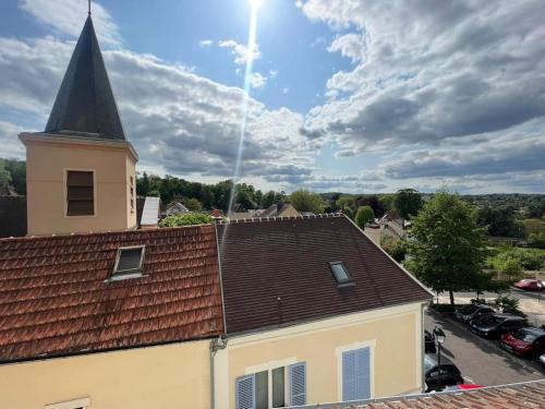 une église avec une cloche au-dessus d'un bâtiment dans l'établissement Au cœur du Bourg - La Celle St Cloud., à La Celle-Saint-Cloud