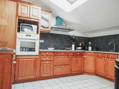 une cuisine avec des placards en bois et un appareil blanc dans l'établissement Appartement avec patio, à Sainte-Anne-d'Auray