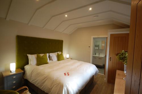 um quarto com uma grande cama branca com almofadas verdes em The Retreat Field View em Great Maplestead
