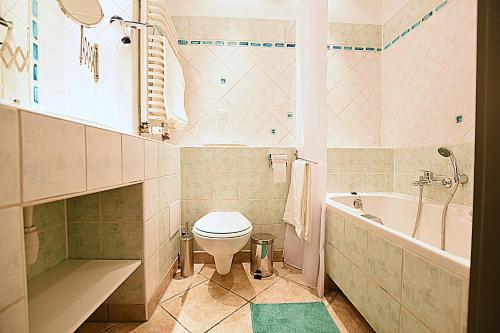 a bathroom with a toilet and a tub and a sink at Mhost Bronowice in Kraków