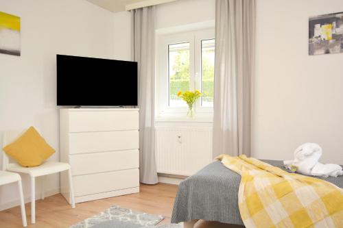 a white bedroom with a television on a dresser at FO02-RI Apartment für Facharbeiter in Forchheim in Forchheim