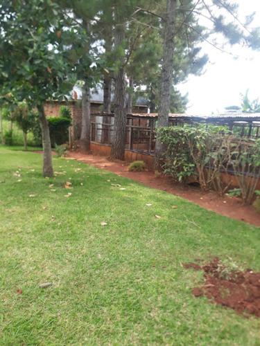 un patio con una casa, árboles y césped en Hfarms Guest House en Wakiso