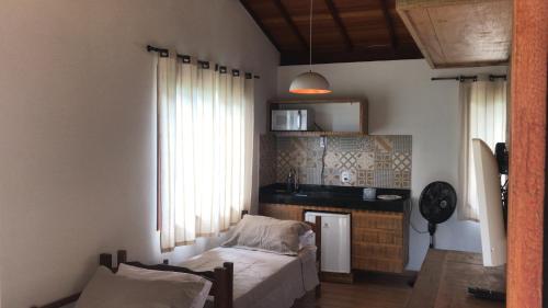 a living room with a bed and a kitchen at Chalés do Recanto in São João del Rei