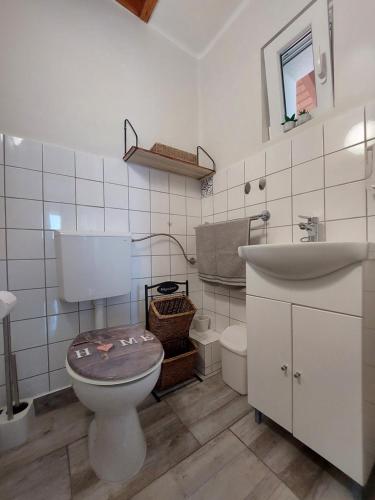 a white bathroom with a toilet and a sink at Laurus Vendéghàz in Lovas