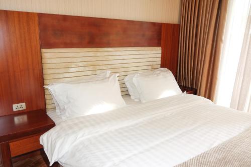 a bedroom with a large white bed with a wooden headboard at Luxury Dreamland Oasis Apartments in Chakvi