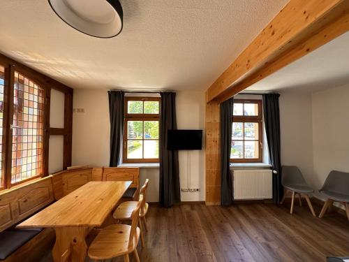 uma sala de jantar com uma mesa de madeira e 2 janelas em Ferienhaus "Kleines Domizil" Altenberg - direkt im Zentrum von Altenberg gegenüber vom Skilift em Kurort Altenberg