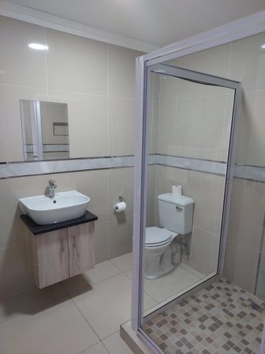 bagno con servizi igienici, lavandino e specchio di Bayside Taj Hotel a Port Shepstone