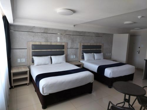 謝普斯敦港的住宿－Bayside Taj Hotel，酒店客房设有两张床和一张桌子。