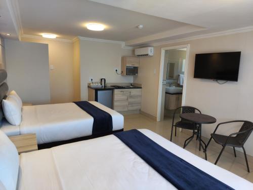 Habitación de hotel con 2 camas y cocina en Bayside Taj Hotel en Port Shepstone