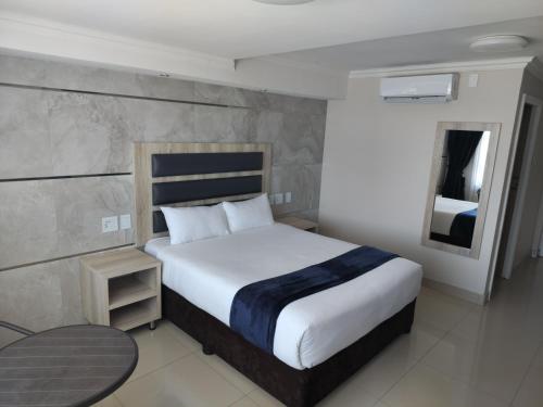 - une chambre avec un lit, une table et un miroir dans l'établissement Bayside Taj Hotel, à Port Shepstone
