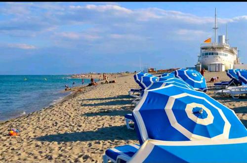 un groupe de parasols bleus sur une plage dans l'établissement Appartement Front de Mer le Barcares, au Barcarès