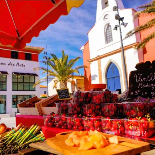 un marché avec des fruits et légumes exposés devant un bâtiment dans l'établissement Appartement Front de Mer le Barcares, au Barcarès