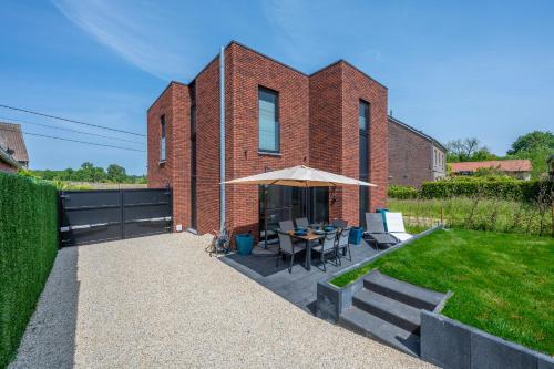 a brick building with a table and an umbrella at unique hideaway, holiday house with large garden in Kortenaken