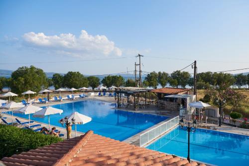 a large swimming pool with umbrellas and chairs at Kalloni Bay in Skala Kallonis