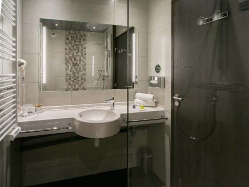 La salle de bains est pourvue d'un lavabo et d'une douche. dans l'établissement B&B HOTEL Strasbourg Nord Schiltigheim Lac 4 étoiles, à Schiltigheim