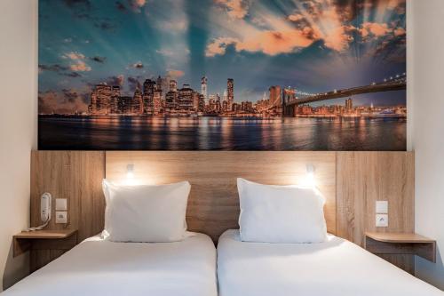- 2 lits dans une chambre d'hôtel avec une photo d'une ville dans l'établissement Kyriad Annemasse - Geneve, à Annemasse