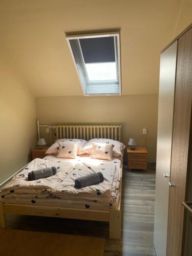 een slaapkamer met een bed met kussens en een raam bij Mini-mál Vendégház in Hajdúszoboszló